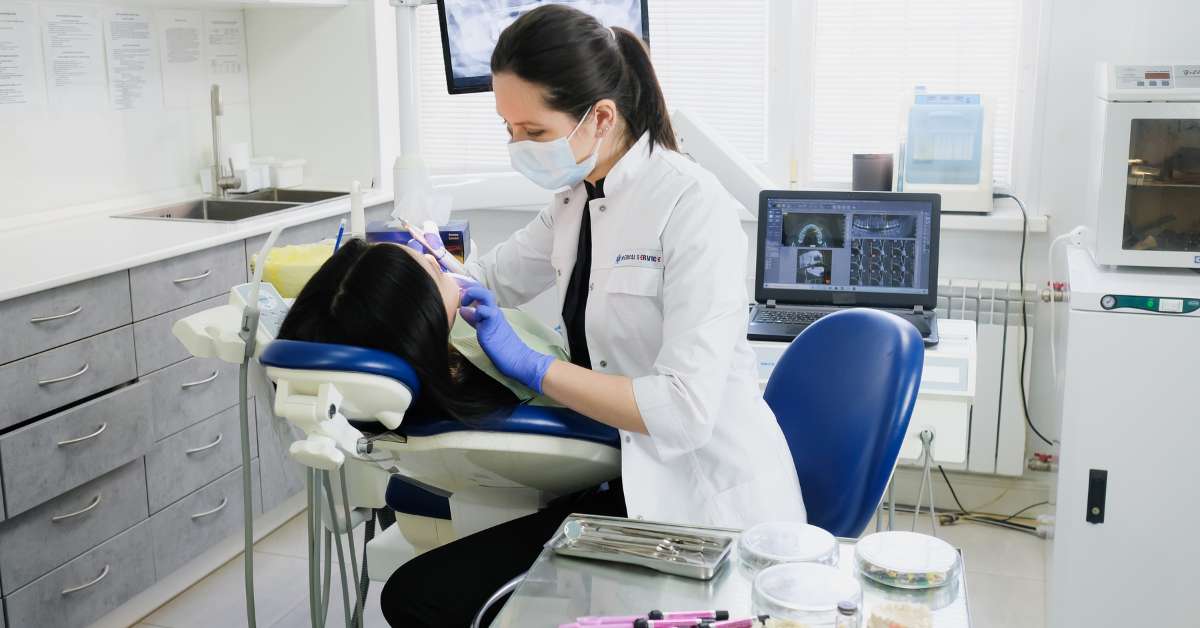 dentist in gloves and mask working on patient in dental chair
